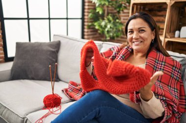 Middle age hispanic woman covering with blanket sewing at home