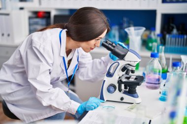 Laboratuvarda mikroskop kullanan genç ve güzel İspanyol bilim kadını.