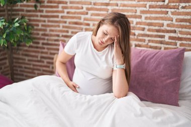 Genç hamile kadın yatakta otururken stresli oluyor.