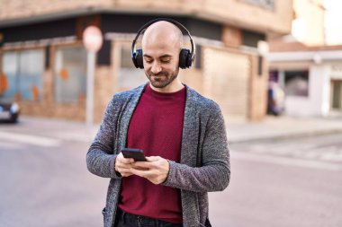 Sokakta müzik dinlerken kendinden emin gülümseyen genç adam.