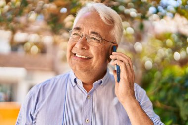 Son sınıf öğrencisi gülümsüyor. Parktaki akıllı telefondan konuşuyor.