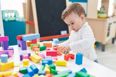 Sevimli beyaz bebek anaokulunda duran inşaat bloklarıyla oynuyor.