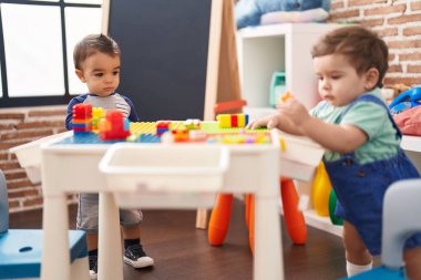 Anaokulunda inşaat bloklarıyla oynayan iki çocuk.