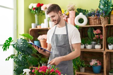 Çiçekçide kendinden emin gülümseyen beyaz bir adam.