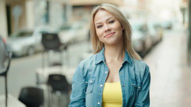 Sokakta kendine güvenen genç sarışın kadın gülümsüyor