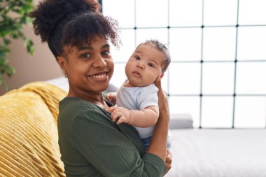 Mother and son hugging each other sitting on sofa at home