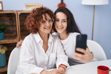 İki kadın anne ve kız evde akıllı telefondan selfie çekiyorlar.