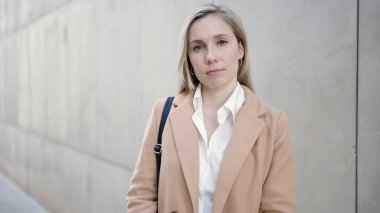 Sokakta ciddi bir ifadeyle duran genç sarışın kadın.