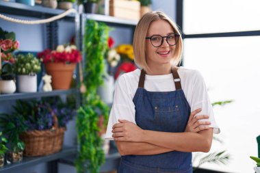 Young blonde woman florist smiling confident standing with arms crossed gesture at florist shop