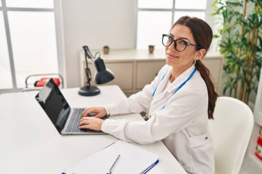 Klinikte çalışan doktor üniforması giyen genç İspanyol kadın.