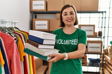 Orta yaşlı İspanyol kadın bağış standında bağış kitapları tutuyor.