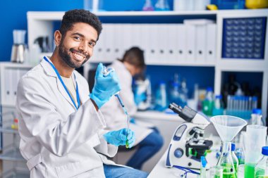 Man and woman scientists pouring liquid on test tube at laboratory