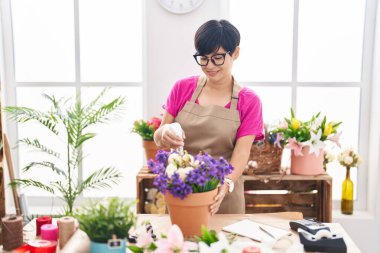 Middle age chinese woman florist using diffuser working at flower shop