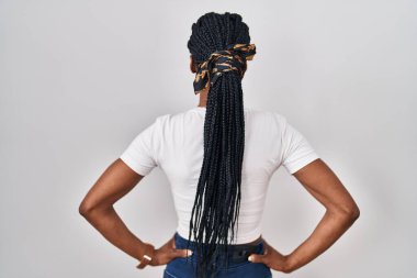 Beautiful black woman standing over isolated background standing backwards looking away with arms on body 