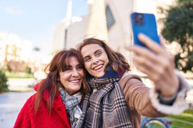 Two women mother and daughter make selfie by smartphone at park
