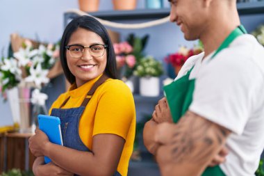 Man and woman florists holding touchpad standing with arms crossed gesture at florist