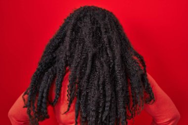 Plus size hispanic woman standing over red background standing backwards looking away with arms on body 