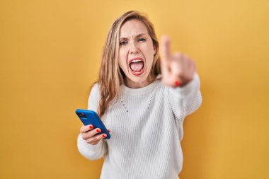 Genç sarışın kadın akıllı telefon kullanarak kameraya rahatsız edici ve hayal kırıklığına uğramış, sana kızgın ve öfkeli bir şekilde mesaj yolluyor. 