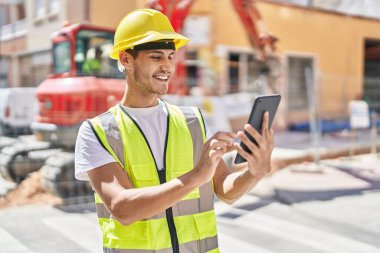 Young hispanic man architect using touchpad at park