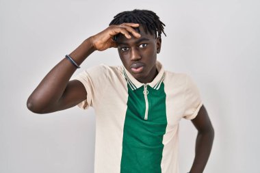 African man with dreadlocks standing over isolated background worried and stressed about a problem with hand on forehead, nervous and anxious for crisis 
