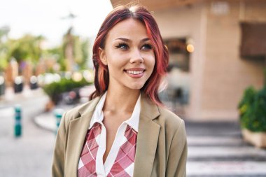 Beyaz kadın gülümsüyor. Kendinden emin. Caddenin kenarına bakıyor.