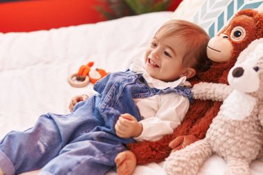 Sevimli sarışın bebek yatak odasında oyuncaklarla oynuyor.