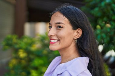 Young beautiful hispanic woman smiling confident looking to the side at street
