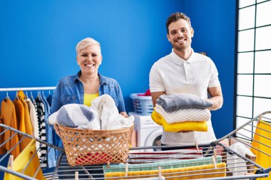 Hispanic mother and son hanging clothes at clothesline smiling with a happy and cool smile on face. showing teeth. 