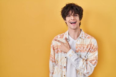 Gündelik yaz gömleği giyen genç adam neşeli, yüzünde mutlu ve doğal bir ifadeyle elleri ve parmaklarıyla yüzünü gösteren bir gülümseme var. 