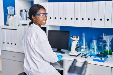 Young african american woman scientist smiling confident working at laboratory