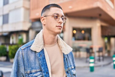 Young hispanic man looking to the side with relaxed expression at street
