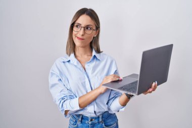 Young woman working using computer laptop smiling looking to the side and staring away thinking. 