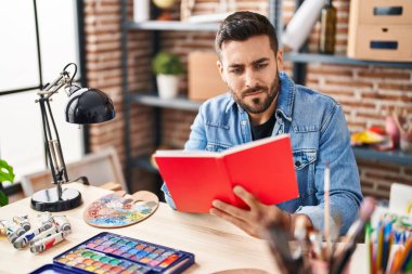 Sanat stüdyosundaki masada kitap okuyan genç bir İspanyol.