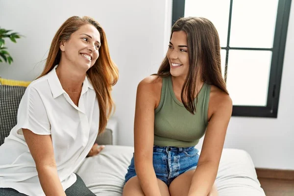 Mother and daughter smiling confident sitting on sofa at home