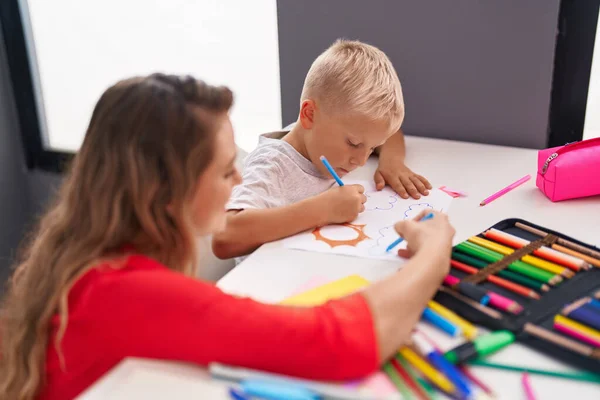 教師と幼児は教室で紙の上に絵を描く — ストック写真