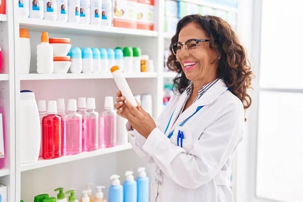 Middle Age Woman Pharmacist Holding Sunscreen Bottle Pharmacy — Zdjęcie stockowe