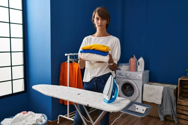 Brunette woman holding folded laundry after ironing skeptic and nervous, frowning upset because of problem. negative person. 