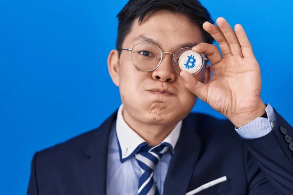 Young Asian Man Holding Virtual Currency Bitcoin Covering Eye Puffing —  Fotos de Stock