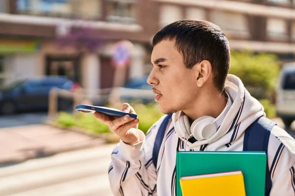 ストリートで本を持っているスマートフォンで話している若い男の学生 — ストック写真