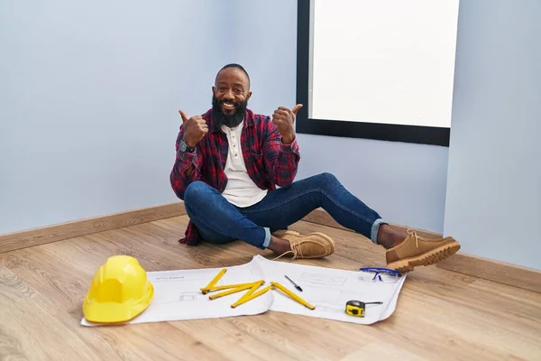 African American Man Sitting Floor New Home Looking Blueprints Success — стоковое фото