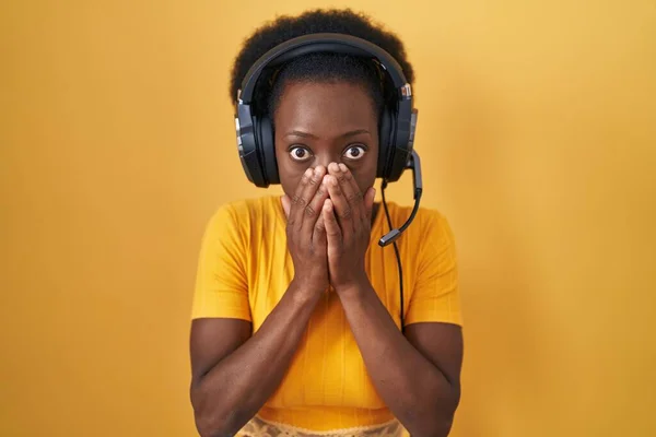 African Woman Curly Hair Standing Yellow Background Wearing Headphones Shocked — Stock Photo, Image