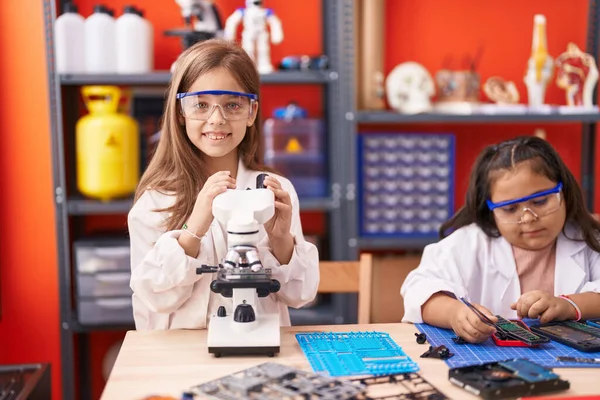 Two kids students using microscope repairing smartphone at laboratory classroom