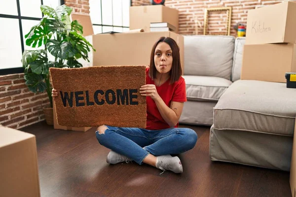 Young Hispanic Woman Holding Welcome Doormat New Home Making Fish — Stockfoto