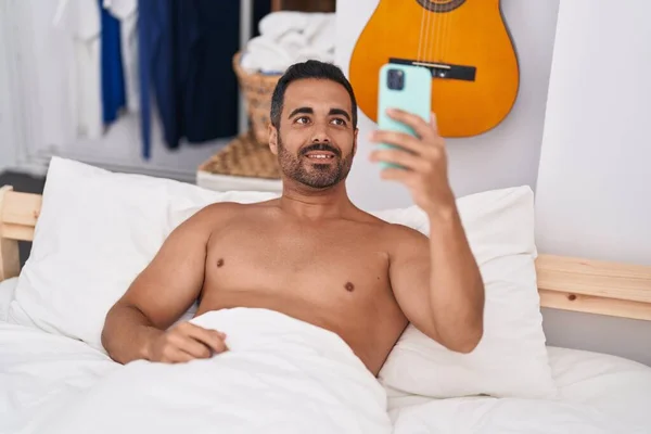 Young Hispanic Man Make Selfie Smartphone Lying Bed Bedroom — стоковое фото
