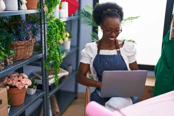 African american woman florist smiling confident using laptop at florist store