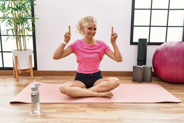 Middle Age Blonde Woman Sitting Yoga Mat Smiling Amazed Surprised — Stock Photo, Image
