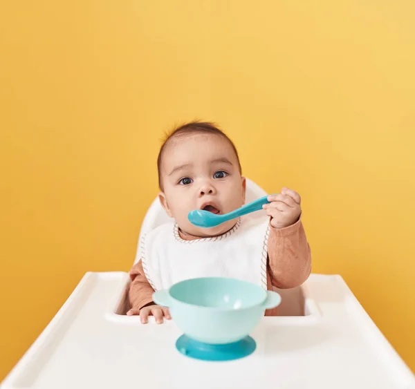 Adorável Criança Hispânica Sentada Cadeira Alta Comendo Sobre Fundo Amarelo — Fotografia de Stock