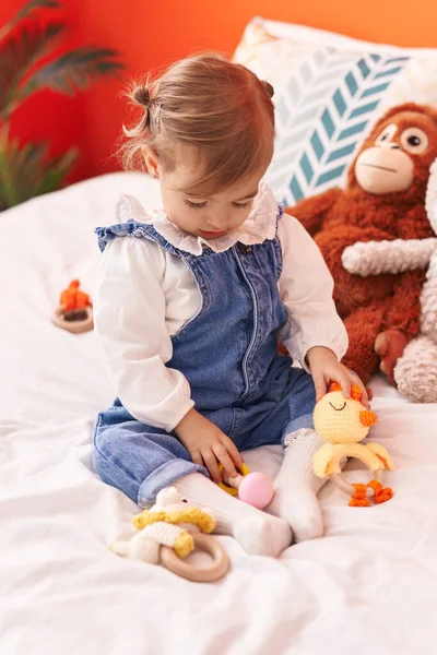 可爱的金发碧眼的幼儿坐在卧室的床上玩玩具 — 图库照片