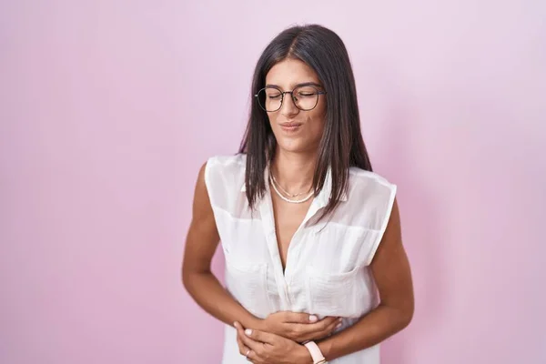 Brunette Young Woman Standing Pink Background Wearing Glasses Hand Stomach — Stockfoto
