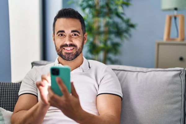Hombre Hispano Joven Usando Teléfono Inteligente Sentado Sofá Casa —  Fotos de Stock